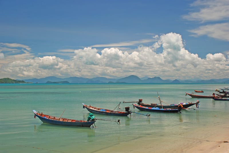 Phuket beach with longtail boats and coastal views